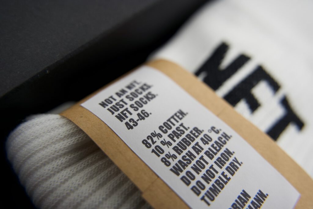 Closeup photo of a sock in a box with label, the sock has the typo "NFT" on it