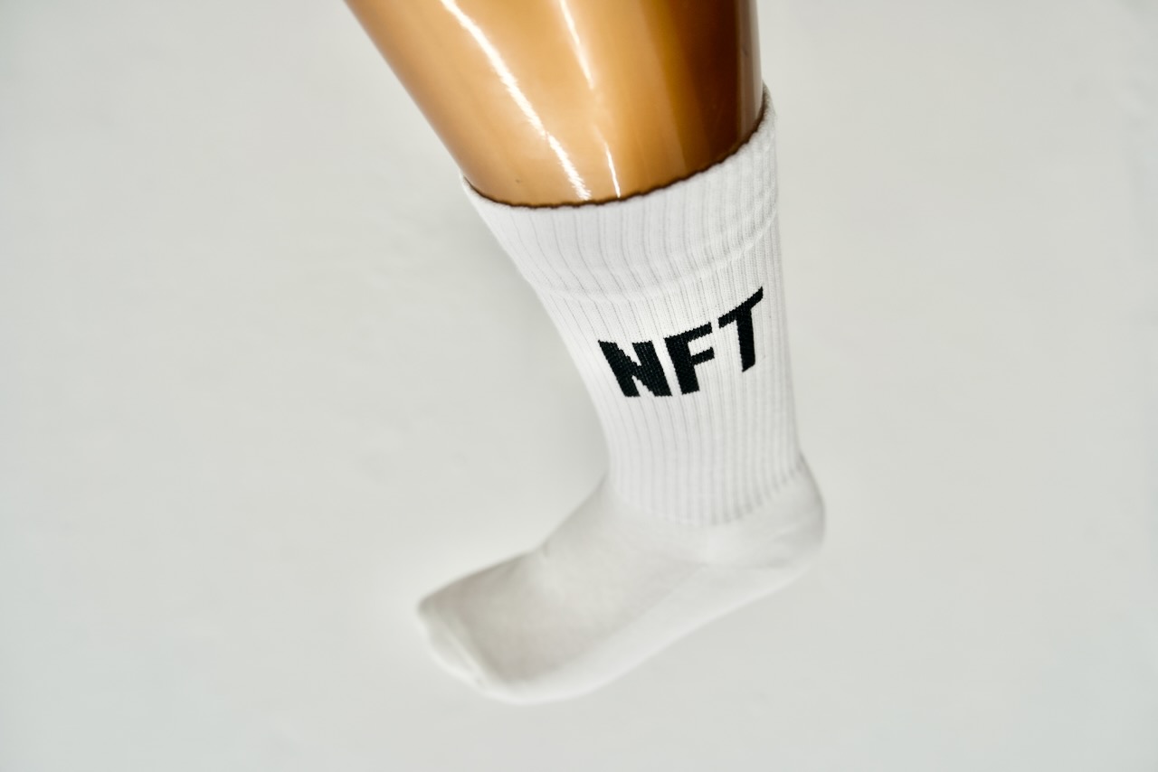 Photo of a bronze leg coming in from the top of the frame, the sock has the typo "NFT" on it