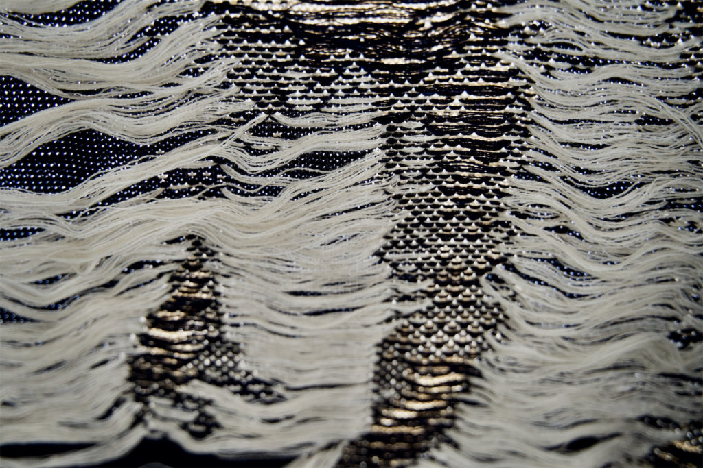Detail of the backside of a black and white machine-knitted blanket.